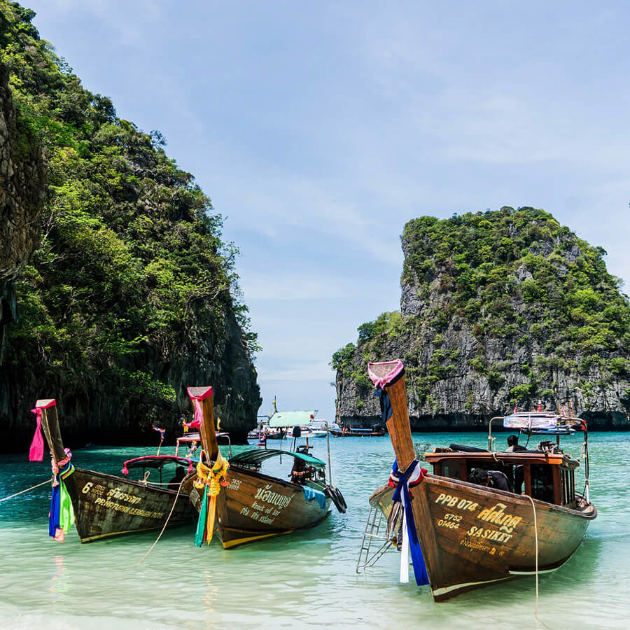 Fischerboote im Vordergrund mit Blick auf das Meer von Phuket mit 2 Felsen im Vordergrund