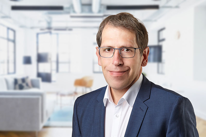 Portrait von Oliver Mück vor einem wohnlichen, hellen Hintergrund
