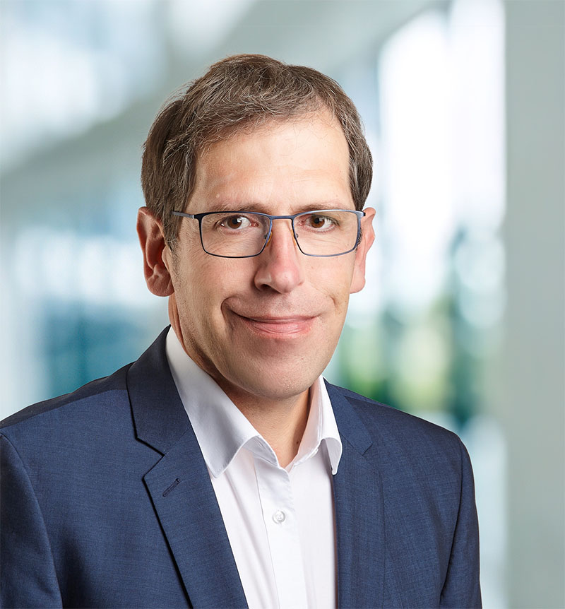 Portrait von Oliver Mück vor einer Fensterfront