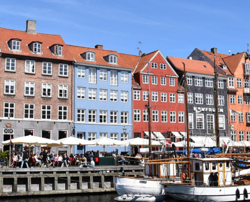 Blick auf Nyhavn mit einem Schiff und Restaurantsterrassen Kopenhagen Dänemark buchbar bei Olivers Touristik World