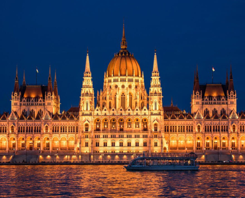 Blick auf dasParlamentsgebäude am Ufer der Donau beleuchtet am Abend buchbar bei Olivers Touristik World