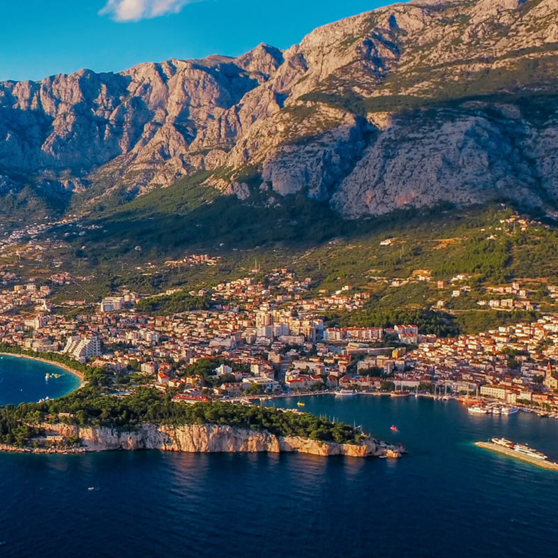 Blick über das Meer auf Makarska und die Berge des Biokovo-Gebirges an der Makarska Riviera in Kroatien