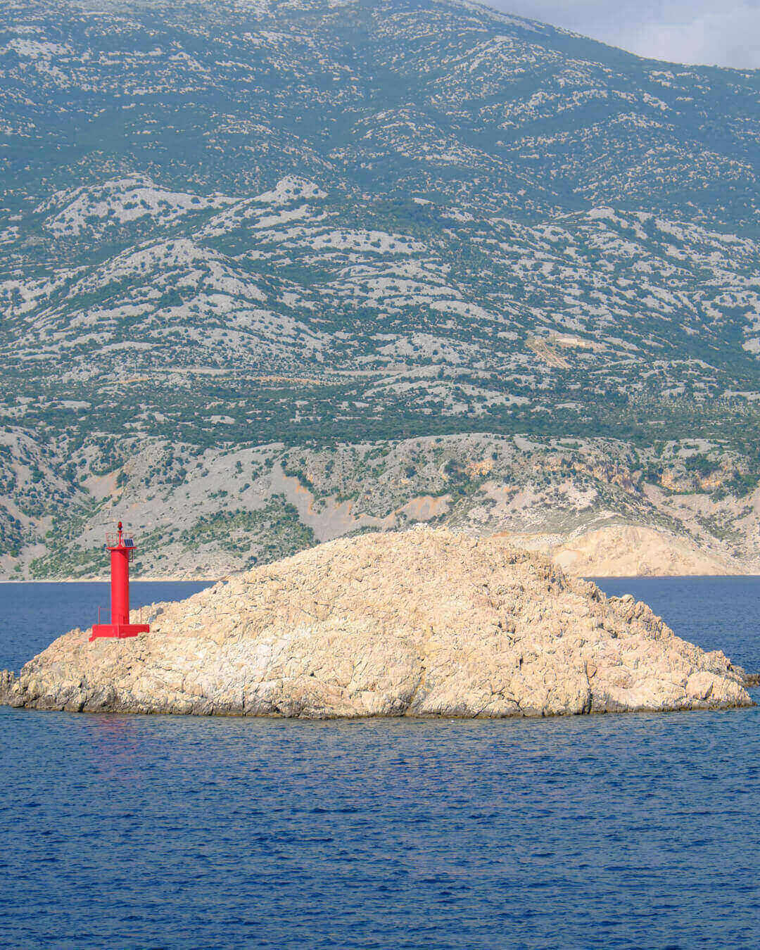 Blick auf einen Felsen mit Leuchtturm und das Velebit Gebirge auf der Insel Pag in der nähe von Zadar in Kroatien Blick auf einen Felsen mit Leuchtturm und das Velebit Gebirge auf der Insel Pag in der nähe von Zadar in Kroatien