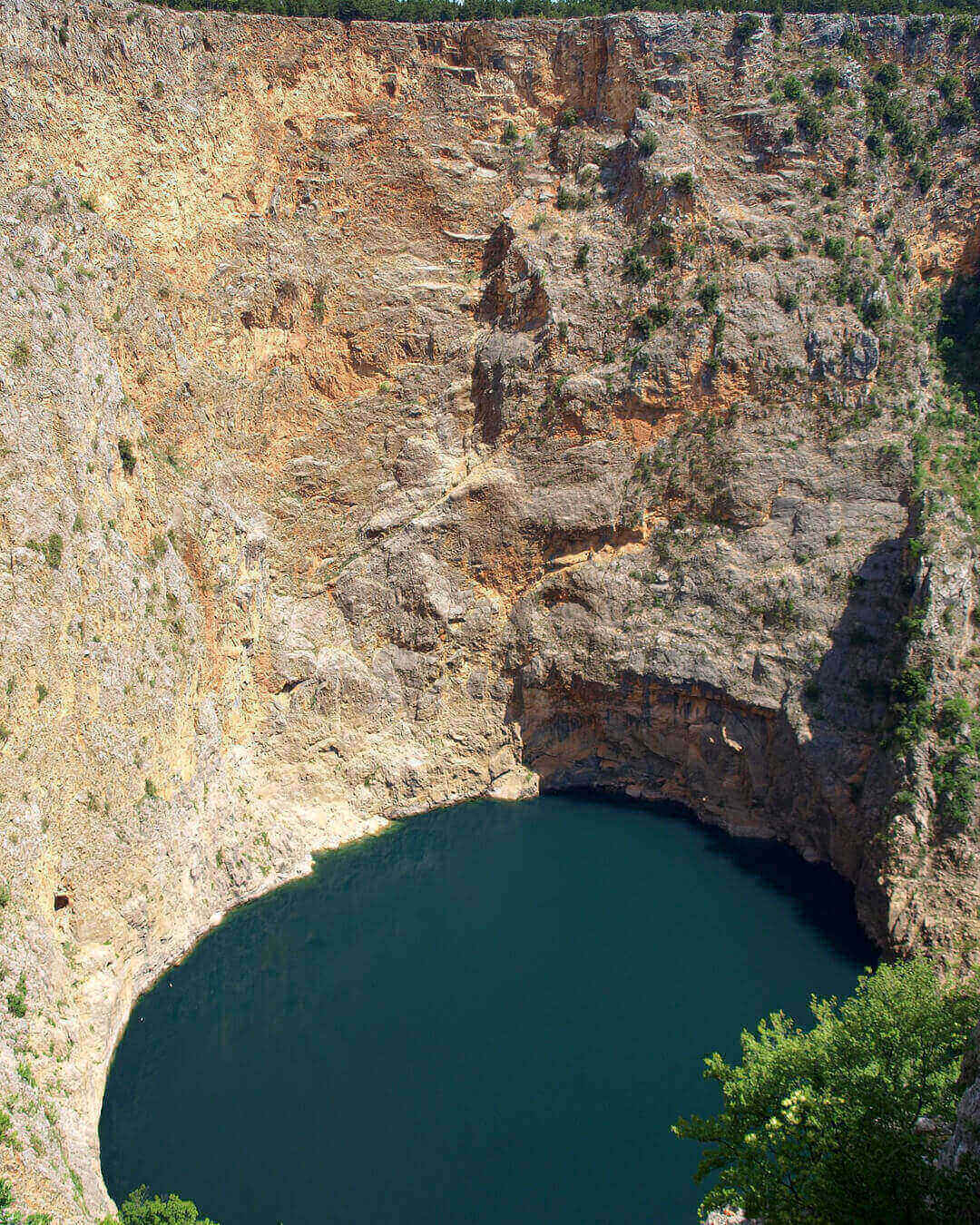 Blick auf die rötlich wirkenden Karstwände des roten Sees unten das Wasser in Imotski in Kroatien Blick auf die rötlich wirkenden Karstwände des roten Sees unten das Wasser in Imotski in Kroatien